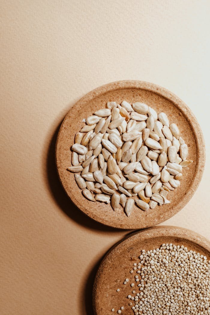 A close-up view of peeled sunflower seeds and quinoa on a wooden plate.